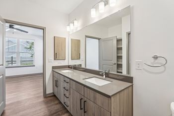 A bathroom with a sink, mirror, and wooden cabinets. at The Junction at Rockledge Apartments, Rockledge, FL